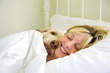 Woman lies in bed with her dog at their home, Lincoln, Nebraska, United States of America