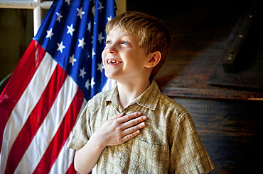 Young, patriotic boy stands before the American flag, Lincoln, Nebraska, United States of America