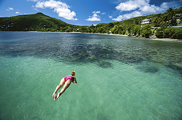 Captured in mid-air, a diver plunges towards tropical waters, Bequia, Saint Vincent and the Grenadines, West Indies