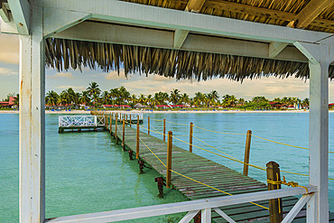 Pier of a hotel at sunset on Cayo Guillermo in the Jardines del Rey archipelago, with clear turquoise water and palm trees on the shore, Cayo Guillermo, Cuba