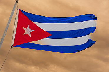 Cuban flag flying proudly against an overcast sky at twilight, Cayo Guillermo, Cuba