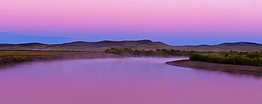 Onan River at dawn in Northeastern Mongolia, with pink light in the sky and reflected in the tranquil water. Chingiss Khan is reputed to have been born near the Onon River, Mongolia