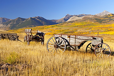 Old horse-drawn wagons with the Rocky Mountains in the Background, near Waterton Lakes National Park, Alberta, Canada, North America