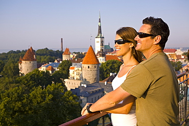 A couple take in the views of lower Old Town with Oleviste Church in the background, Tallinn, Estonia, Europe