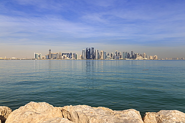 Modern city skyline of West Bay, across the calm turquoise waters of Doha Bay, from the Dhow Harbour, Doha, Qatar, Middle East