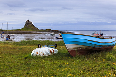 Fishing boats onshore and beach at low tide with Lindisfarne Castle and Farne Islands, Holy Island, Northumberland, England, United Kingdom, Europe