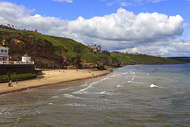 Bathers on West Cliff Beach, backed by grassy cliffs in summer, Whitby, North Yorkshire, England, United Kingdom, Europe