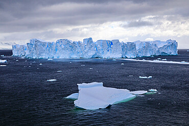 Large blue tabular iceberg, small iceberg and coast of Errera Channel, Danco Coast, Antarctic Peninsula, Antarctica, Polar Regions