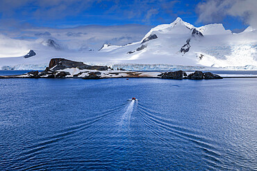 Tourists on a zodiac boat approach Half Moon Island, Livingston Island mountain backdrop, South Shetland Islands, Antarctica, Polar Regions