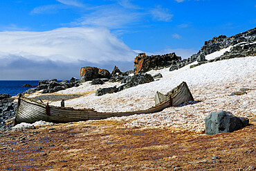 Handsome derelict wooden boat on Half Moon Island snowy shore, blue sky and sun, South Shetland Islands, Antarctica, Polar Regions