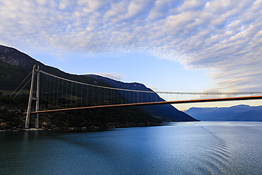 Passing under the huge Hardanger Bridge, sunrise, beautiful dawn clouds, Hardangerfjord, Norwegian Western Fjords, Norway, Scandinavia, Europe