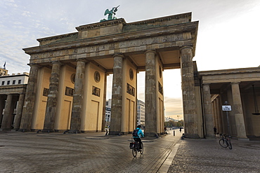 Cyclist approaches the Brandenburg Gate in the early morning, Historic Mitte, Berlin, Germany, Europe