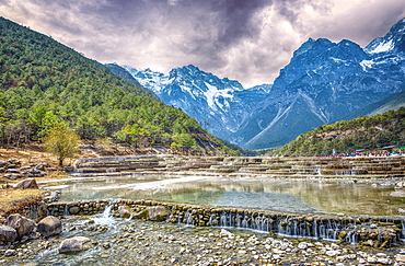 HDR image of cascading falls at Baishuihe, or White Water River with Jade Dragon Snow Mountain, Lijiang, Yunnan, China, Asia