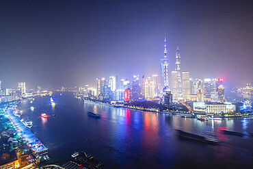 The illuminated skyline of Pudong district in Shanghai with the Huangpu River in the foreground, Shanghai, China, Asia