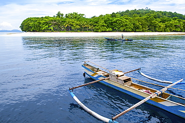 A local fisherman and a traditional outrigger canoe off the beach, Molana Island, Ambon, Maluku, Spice Islands, Indonesia, Southeast Asia, Asia