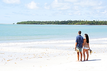 A good-looking Hispanic (Latin) couple on a deserted beach with backs to camera, Brazil, South America