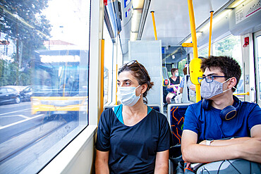 A mother and son wearing health protection masks on a public tram (trolley car), Lisbon, Portugal, Europe