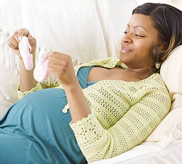 Pregnant African American woman holding booties