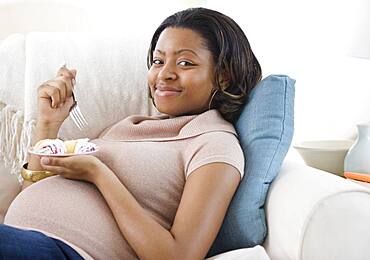 Pregnant African American woman eating cake