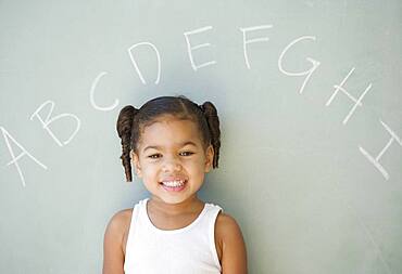 African girl leaning against blackboard