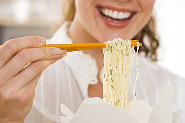 Close up of woman eating noodles with chopsticks