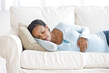 Pregnant African woman sleeping on sofa