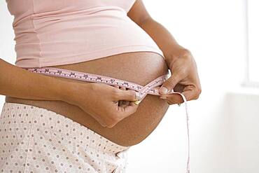 Pregnant African woman measuring belly