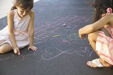 Two girls making chalk drawings