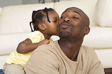 African girl kissing father's cheek