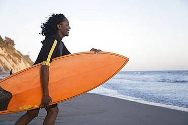 African woman carrying surfboard