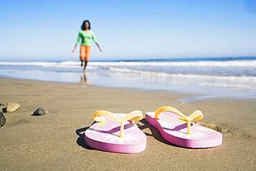 Flip-flops on beach in front of woman