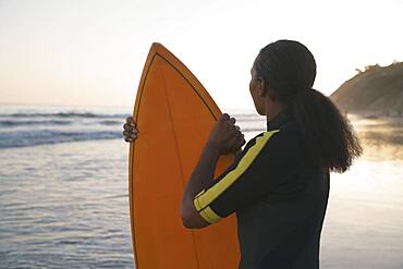 Mixed Race woman holding surfboard