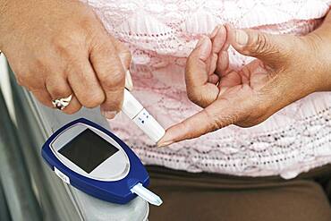 Senior African American woman testing blood sugar