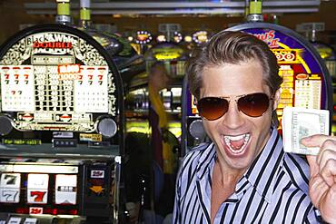 Young man holding his winnings at the casino