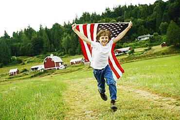 Boy running with American flag at farm