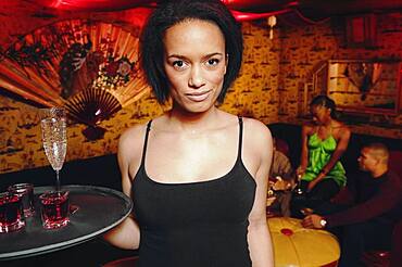 African cocktail waitress holding tray of drinks