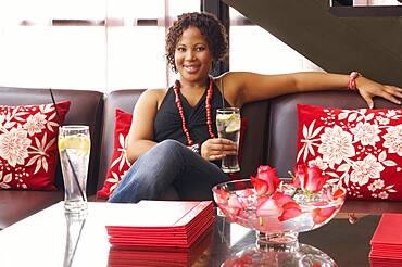 African American woman sitting on sofa with drink