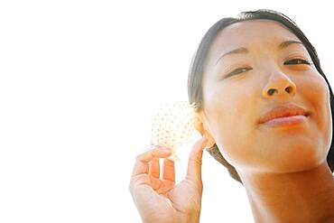 Asian woman listening to seashell