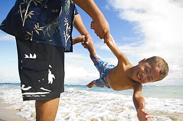 Pacific Islander father and son playing at beach