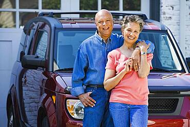 Senior African American couple leaning on car