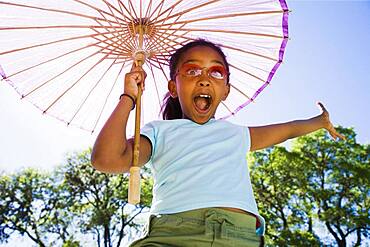 African American girl laughing with parasol outdoors