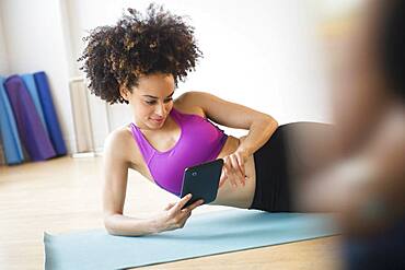 Mixed race woman working out with digital tablet in gymnasium