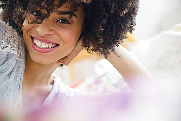 Smiling mixed race woman laying on bed