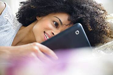 Mixed race woman using digital tablet on bed