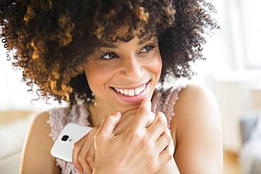 Smiling mixed race woman holding cell phone