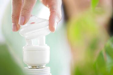 Mixed race woman holding fluorescent light bulb