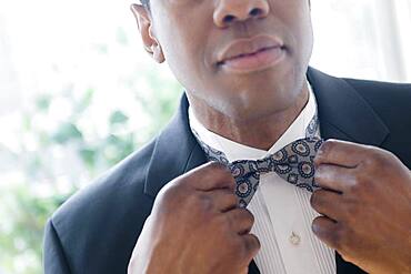 Groom in tuxedo adjusting bow tie