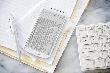 Close up of computer keyboard, files and cell phone on office desk