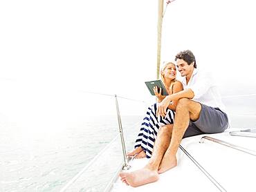 Couple using digital tablet boat deck