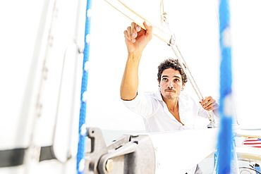 Hispanic man adjusting rigging on sailboat